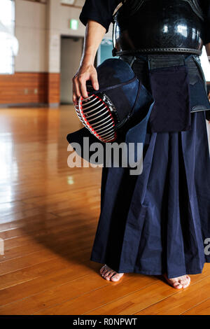 Männliche japanische Kendo Kämpfer stehen ein Fitnessraum, holding Kendo mask. Stockfoto