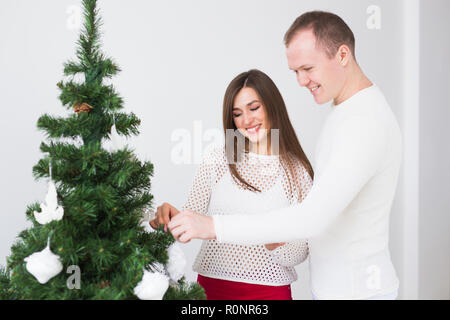 Winterurlaub und Personen Konzept-liebenden Paar hängende Dekorationen auf Weihnachtsbaum Stockfoto