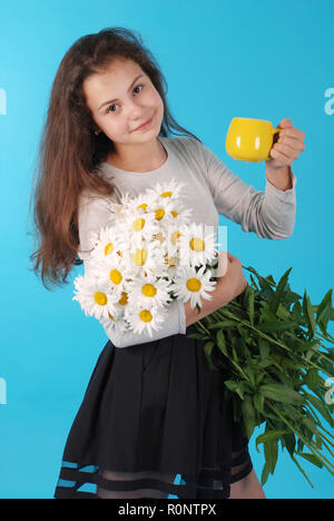 Junge Mädchen trinken Kamillentee auf blauem Hintergrund im Studio. Gesunder Lebensstil Konzept. Stockfoto