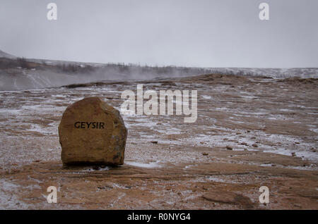 Roter Stein mit der Aufschrift GEYSIR steht auf heiße Erde in das Tal der Geysire in Island Stockfoto