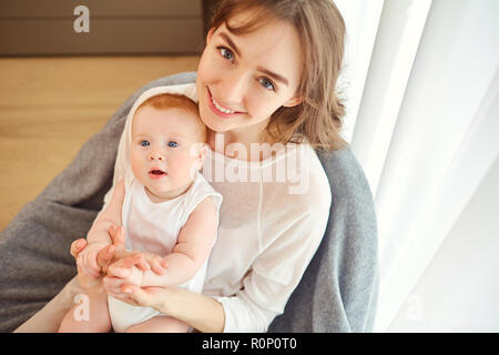 Eine Mutter mit einem Baby auf dem Arm sitzt auf einem Stuhl. Stockfoto