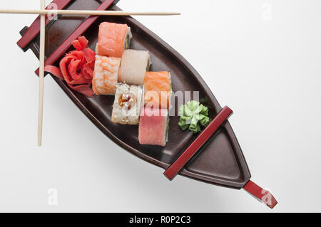 Nahaufnahme der sashimi Sushi mit Stäbchen und Soja auf einem schwarzen, das Boot Fach eingestellt Stockfoto