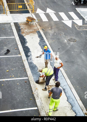 Arbeiter die manuelle Anwendung von frischem Asphalt während der Herstellung einer Fußgängerzone. Stockfoto