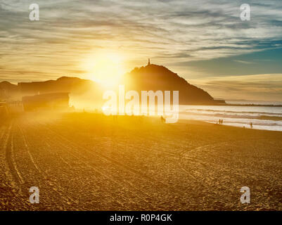 Die Sonne hinter dem Monte Urgull von San Sebastian, Baskenland, Guipuzcoa. Spanien. Blick vom Strand Zurriola. Stockfoto