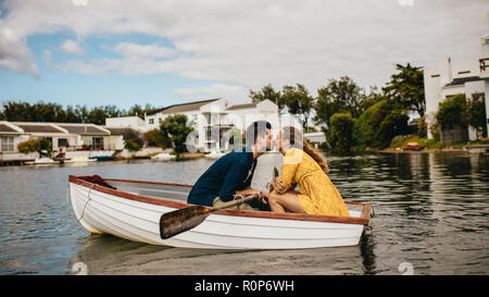 Romantisches Paar Bootfahren in einem See Zeit miteinander zu verbringen. Mann küsste seine Freundin während auf ein Datum in einem Boot sitzen. Stockfoto