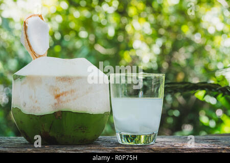 Frische organische Kokosnuss Wasser in das Glas auf Holz- Tabelle. Stockfoto