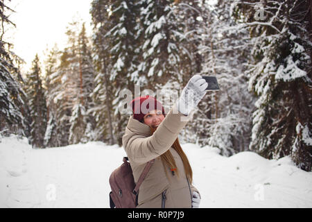 Junge Frau, die auf einem Hintergrund von selfie schnee winter Pinienwald. Das eisige Wetter. Big Pines. Winterurlaub Stockfoto