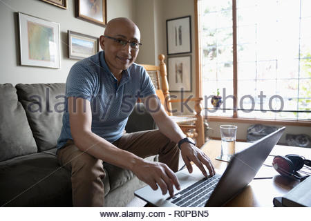 Portrait zuversichtlich Latinx Mann mit Laptop im Wohnzimmer