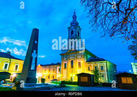 Nachtaufnahme der Reformierten Kirche und zentralen Kreuz Denkmal der Stadt, in Baia Mare, Rumänien Stockfoto