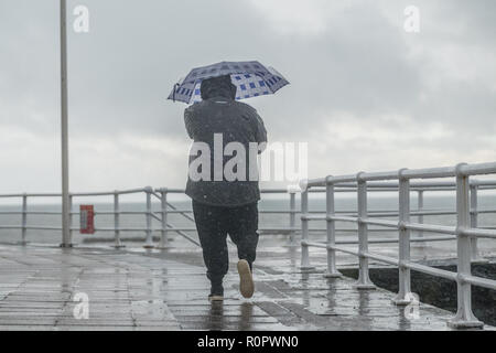 Aberystwyth, Wales, UK. 7. November 2018. UK Wetter: Menschen zu Fuß im Regen auf einer sehr nass, aber mild, morgen in Aberystwyth. Das Met Office hat eine gelbe Warnmeldung für Regen und Überschwemmungen, die viel von Süd und West Wales heute morgen, mit einer weiteren Warnung für mehr Regen und Sturm Winde für den gleichen Bereich am Freitag gab auch ausgestellt. Foto: Keith Morris/Alamy leben Nachrichten Stockfoto