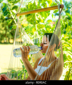 Junge Frau trinkt Mineralwasser aus Plastikflaschen, tropischen Garten, Guadeloupe, Französisch Westindien, Stockfoto