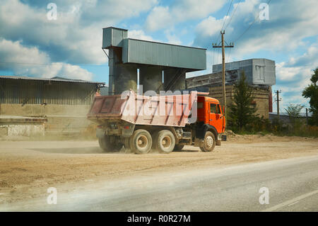 Red Big Truck vor dem Hintergrund einer Fabrik und der Himmel mit Wolken. Stockfoto