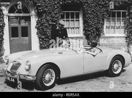 MG in den 1950er Jahren. Britische Automobilhersteller MG startet das neue Modell Sport MGA. Das Auto hat eine vier-cylindre Motor. Ein junges Paar Posen mit dem Auto in einer typischen Umgebung. Stockfoto