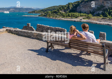 Junges Paar auf einer Bank sitzen bewundert den Blick auf den Golf der Poeten in Portovenere mit einem Kreuzfahrtschiff im Hintergrund, Ligurien, Italien Stockfoto