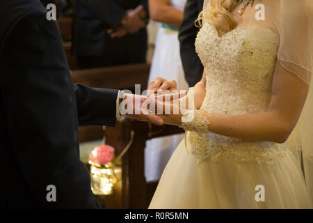 Nahaufnahme der Braut die Hochzeit Ring auf ihrem Bräutigam Finger auf ihre Hochzeit in England Stockfoto