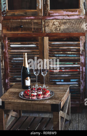 Leckere Cupcakes und Champagner für Zwei auf den Jahrgang Holztisch Stockfoto