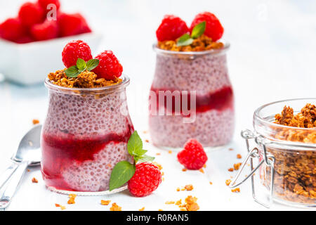 Serviert Glas Gläser mit köstlichen Chia Pudding mit Himbeeren und crunchy Granola oben gefüllt Stockfoto