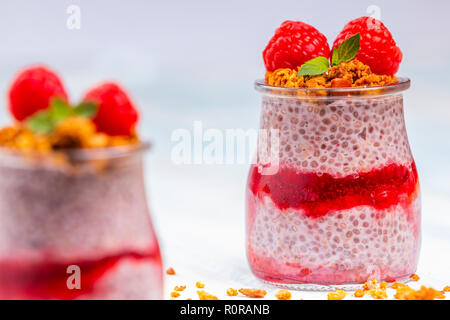 Serviert Glas Gläser mit köstlichen Chia Pudding mit Himbeeren und crunchy Granola oben gefüllt Stockfoto