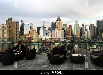 Junge Paare teilen einen Kuss und Champagner in der Presse Lounge Bar auf der Dachterrasse vor der Skyline von Manhattan in den frühen Abend, New York, NY Stockfoto