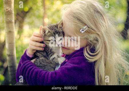 Schöne blonde Mädchen, dass eine flauschige Katze und zusammen kuscheln Stockfoto