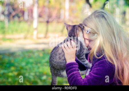 Schöne blonde Mädchen, dass eine flauschige Katze und zusammen kuscheln Stockfoto