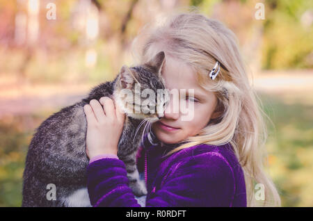 Schöne blonde Mädchen, dass eine flauschige Katze und zusammen kuscheln Stockfoto