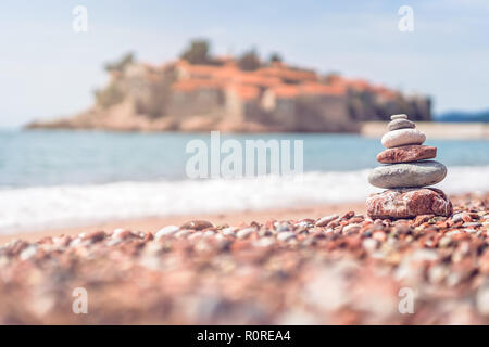 Stapel aus gestapelten Steinen am Strand vor der historischen Sveti Stefan Altstadt, Küste von Montenegro Stockfoto
