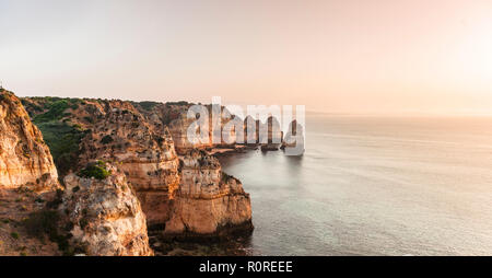 Sonnenaufgang über dem Meer, an der felsigen Küste von Sandstein, Felsformationen im Meer, Algarve, Lagos, Portugal Stockfoto