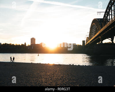 Brücke über den Rhein in Köln bei Sonnenuntergang mit zwei Silhouetten der Frau sprechen Stockfoto