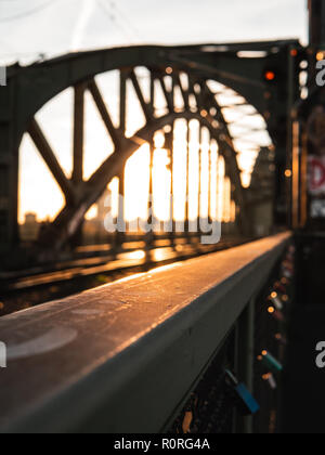 Geländer einer Brücke bei Sonnenuntergang, mit Brücke unscharf im Hintergrund. Köln, Deutschland. Stockfoto