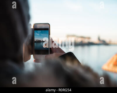 Junge Frau, die Bilder von der Skyline von Köln mit ihrem Smartphone Stockfoto