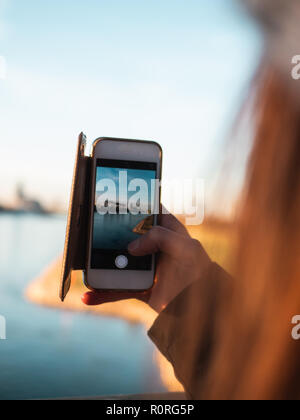 Junge Frau, die Bilder von der Skyline von Köln mit ihrem Smartphone Stockfoto