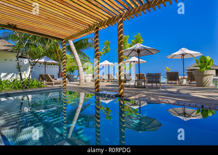 Die Liegestühle am Pool, Spa und Entspannung im Freien Holzterrasse, Palmen und Liegestühlen ausgestattet. Luxuriöses Hotel und Resort entspannende Hintergrund. Stockfoto