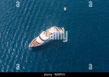 Aerial drone Vogelperspektive top anzeigen Foto Luxus Yacht mit Holzterrasse im tiefen blauen Wasser der Insel Mykonos, Kykladen, Griechenland Stockfoto