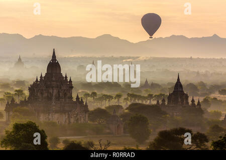 Heißluftballon fliegen über Pagoden an Misty Dawn in der Ebene von Bagan, Myanmar (Birma) Stockfoto