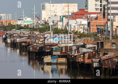 Slum Holzhaus auf dem Saigon River Bank, vor modernen Gebäuden, in Ho Chi Minh City, Vietnam Stockfoto