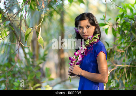 Schließen sie sich hübsche Asiatin in blauem Kleid Holding Frisches lila Blüte, während in die Kamera schaut. Stockfoto