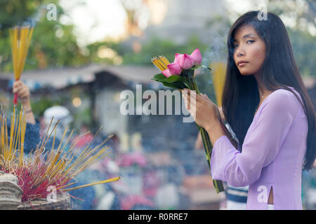 Vietnamesische Frau im Tempel beten, Räucherstäbchen und Lotus Blumen Stockfoto