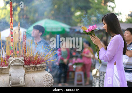 Vietnamesisches Mädchen im Buddhistischen Tempel beten, holding Lotus Blumen, Saigon, Vietnam Stockfoto