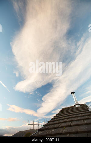 Hohe Wolken und Kondensstreifen auf Ambleside, Lake District, England mit einem Haus Dach mit Solarzellen. Stockfoto