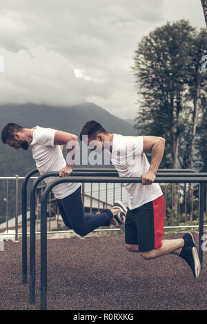 Zwei Sportler tun Dips am Barren Stockfoto