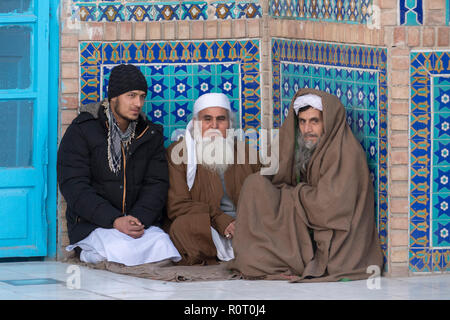 Drei Männer sitzen in einer Nische im Heiligtum von Hazrat Ali, auch genannt die Blaue Moschee, Mazar-e-Sharif, Afghanistan Stockfoto