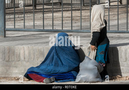 Mutter, die traditionelle Blaue Burka auf der Erde, in einem Park mit ihrer Tochter in der Nähe stehen, Mazar-e Sharif, Provinz Balkh, Afghanistan Stockfoto