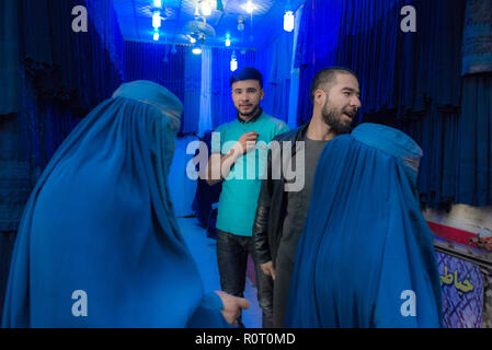 Zwei Frauen in einem blauen Burka Shop mit zwei Männer an der Mazar-e Sharif zentralen Basar, maraz-e Sharif, Provinz Balkh, Afghanistan Stockfoto