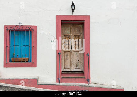 Eine alte hölzerne Tür mit Rosa und blauen Fensterläden auf ein historisches Haus in San Miguel de Allende, Mexiko. San Miguel de Allende hat mehr als 2.000 alte hölzerne kolonialen Türen aus dem Jahr 1800 macht die Stadt einzigartig in Mexiko. Stockfoto