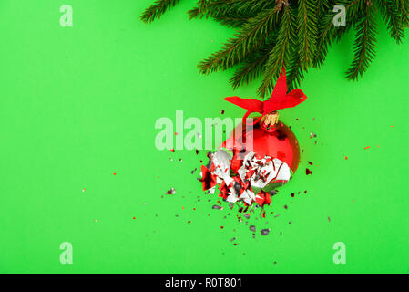 Gebrochener roter Christmas Ball auf grünem Hintergrund mit tree branch Stockfoto