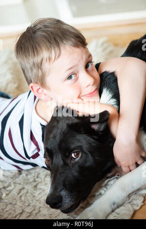 Ein schöner kleiner Junge mit ADHS, Autismus, Asperger-syndrom kuschelt und spielt mit seinem treuen lieben Hund, adorable Stockfoto