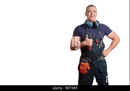 Starke männliche Mechaniker in Blau overal stehend mit orange Handschuhe, weißen Helm, Gehörschutz und Tools auf einem weißen Hintergrund isoliert Stockfoto