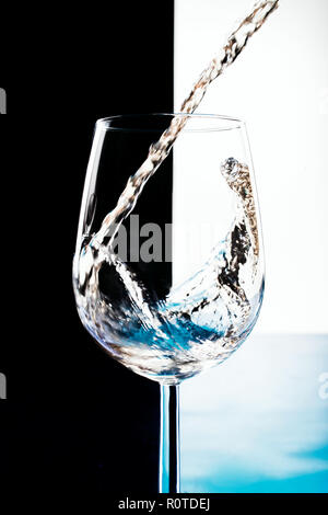 Weißwein wird in ein Glas Becher gegossen Stockfoto
