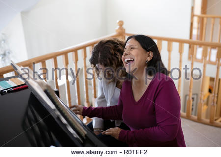 Glückliche, unbeschwerte Latinx Tochter und Mutter Klavier ausüben